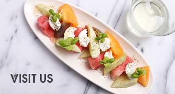 A plate of cheese, fruit, and melon served on a white plate at Boqueria Spanish tapas restaurant located in Washington DC.