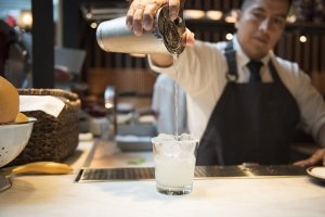 Bartender pours cocktail at Boqueria Spainish tapas bar during happy hour.