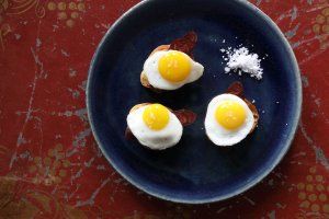 Spanish egg dish on blue plate at Boqueria Spanish tapas restaurant located in NYC and Washington DC with the recipe available in the tapas cookbook, Boqueria: A Cookbook.