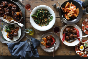 Multiple plates of Spanish cuisine spread out on a table with recipes available in the Spainish cookbook, Boqueria: A Cookbook.